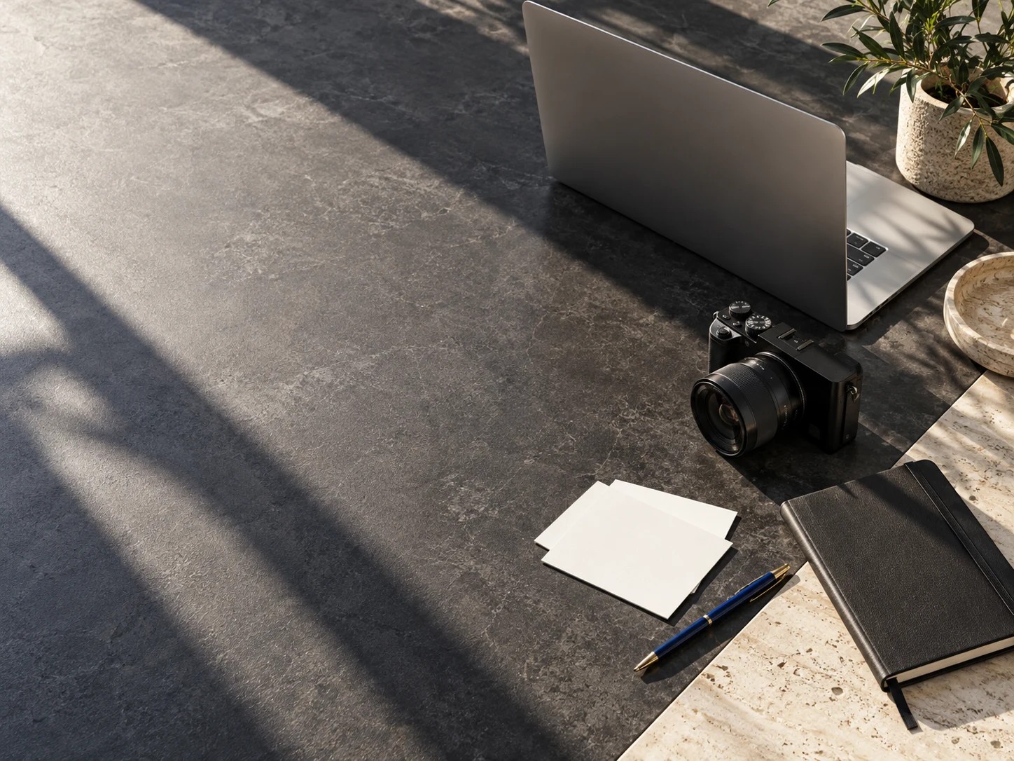 Laptop, camera and stationery on a sunlit creative workspace